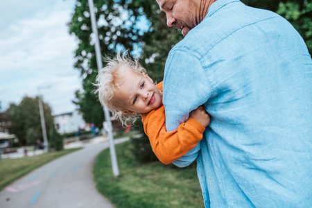 Father playing with toddler son outdoors in parkの写真素材