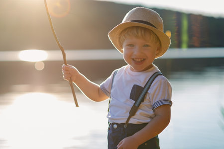 A small toddler boy standing by a lake at sunset. Space for text.の写真素材