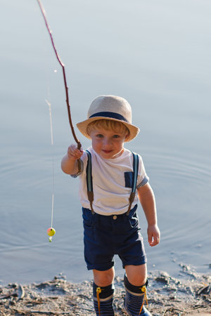 A small toddler boy standing by a lake at sunset. Copy space.の写真素材