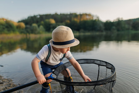 Boy playing with fishing net by the lake, enjoying a carefree moment in nature.の写真素材
