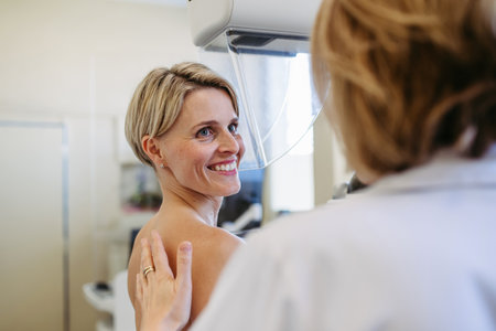 Healthcare professional adjusts the patient for accurate breast imaging.の写真素材
