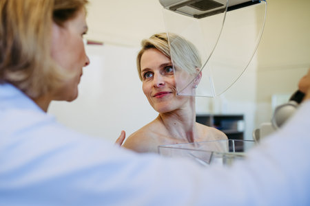 Healthcare professional adjusts the patient for accurate breast imaging.の写真素材