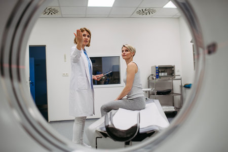 Doctor explaining CT scan procedure to female patient in imaging room