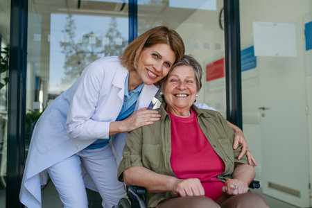 Geriatric doctor talking with patient in a wheelchair in hospital hallway.の写真素材