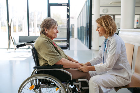 Elderly patient in wheelchair talking with female physician.の写真素材