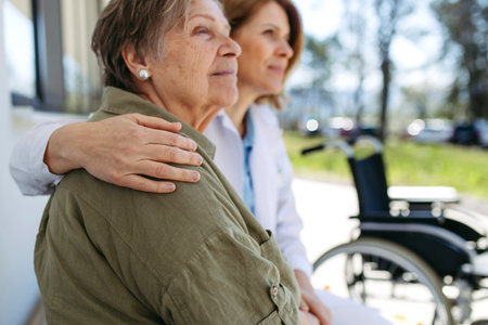 Doctor and elderly patient sitting in front of hospital building and talking.の写真素材