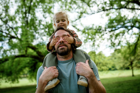 Little boy covering dads eyes, while he carry him on shoulders.の写真素材