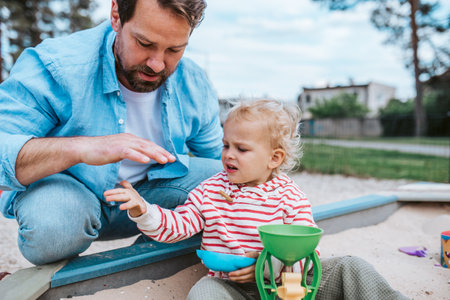 Father and little toddler son playing in the sandbox on playground.の写真素材