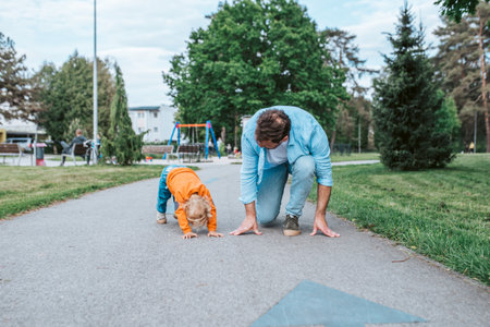 Father lining up to have a running race with his little son.