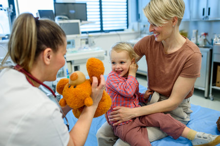 Female pediatrician comforting little boy with teddy bear.の写真素材