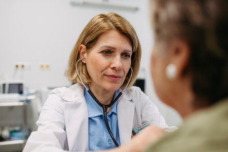 Geriatrician doctor examining elderly patient with stethoscope.の写真素材