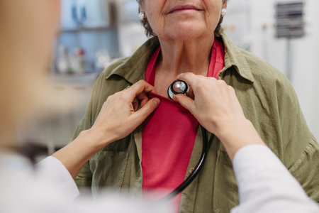 Geriatrician doctor examining elderly patient with stethoscope.の写真素材