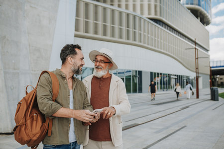 Mature son and father traveling together, looking at map on phone.の写真素材