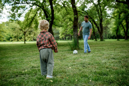 Father and son playing football together in parkの写真素材