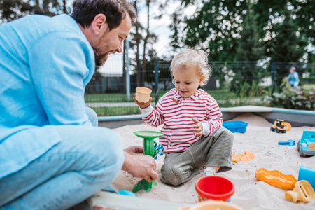 Father and little toddler son playing in the sandbox on playground.の写真素材