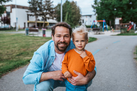 Father playing with toddler son outdoors in parkの写真素材