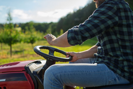Close up of farmer driving small tractor in orchard, enjoying peaceful moment.の写真素材