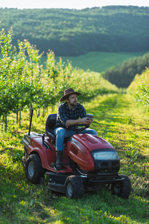 Farmer sitting on small tractor in orchard, enjoying peaceful moment.の写真素材