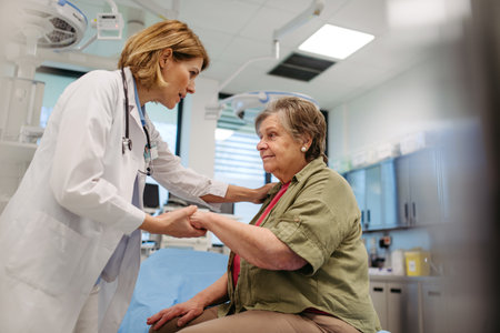 Kind physician comforting elderly patient with gentle hand touchの写真素材