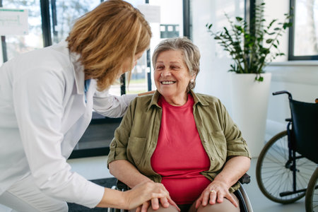 Geriatric doctor talking with patient in a wheelchair in hospital hallway.の写真素材