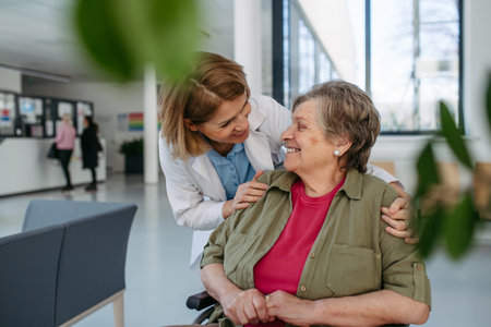 Geriatric doctor talking with patient in a wheelchair in hospital hallway.の写真素材