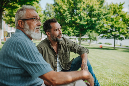 Happy dad and adult son enjoying peaceful afternoon outdoorsの写真素材