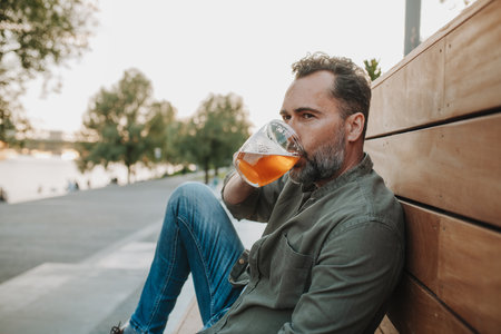 Handsome man drinking beer at outdoor pub, enjoying a peaceful eveningの写真素材
