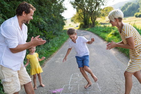 A young family with small children playing hopscotch on a road in summer.の写真素材