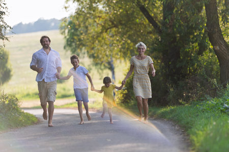 A family with small children running barefoot on a road in summer.の写真素材