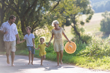 A family with small children running barefoot on a road in summer.の写真素材