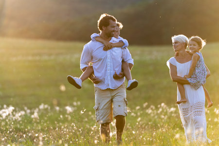 Young family with small children on walk in summer nature at sunset.の写真素材