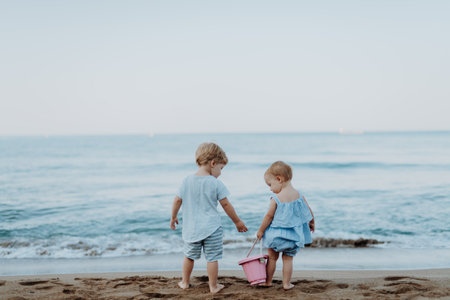 Two toddler children playing on sand beach on summer holiday.の写真素材