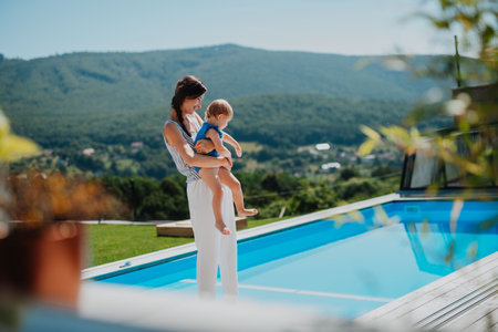 Mom holding little daughter and showing her pool.の写真素材
