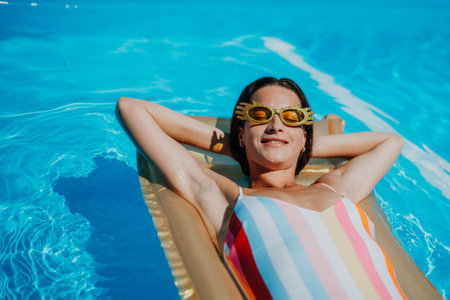 Top view of young woman in swimming pool outdoors on floating bed, relaxing.の写真素材