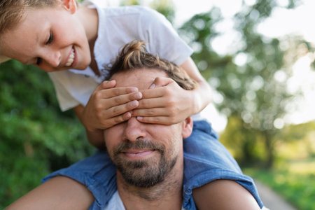 Happy child covering fathers eyes during fun gameの写真素材