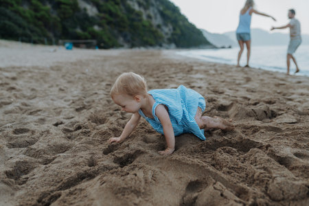 Little girl crawling, playing on sand beach on summer holiday.の写真素材
