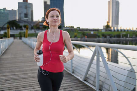sporty woman running across a city bridge during her morning workout.の写真素材