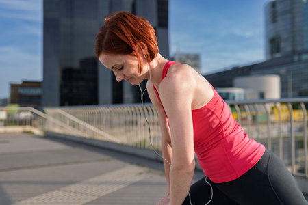Sporty woman runner preparing for morning training, stretching.