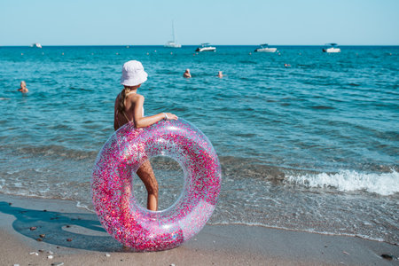 Girl on beach with swim ring during summer beach holiday.