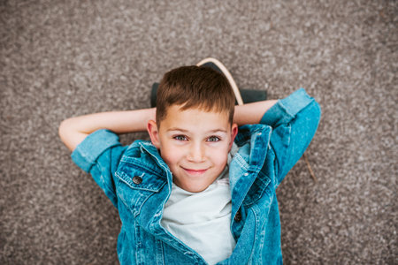 Relaxed boy lying on ground, top view.