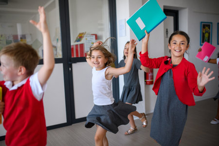 Happy schoolkids in uniforms running down the school hallway.の写真素材