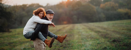 Senior husband piggybacking his wife on back, romantic moment.の写真素材