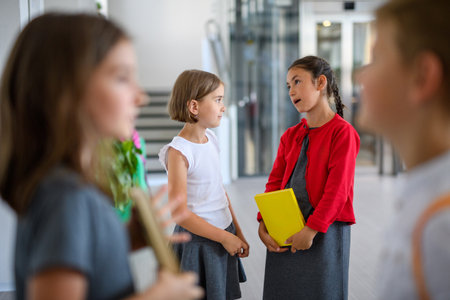 Happy schoolkids talking in school hallway.