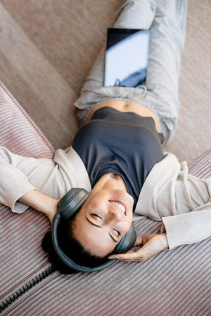 Woman relaxing at home, enjoying music after work.の写真素材