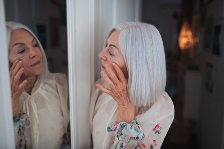 Portrait of elderly woman standing in front mirror.の写真素材