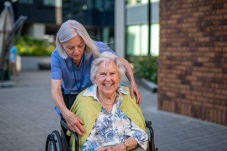 Older caregiver pushing senior woman in wheelchair.