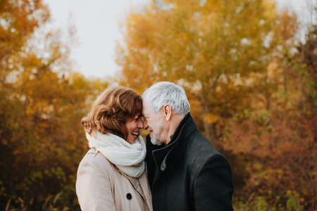 Romantic walk through fall forest by senior couple.