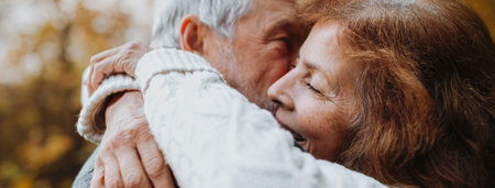 Hugging older couple spending time outdoors in fall season.