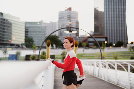 Young woman doing exercise on bridge outdoors in city, stretching.
