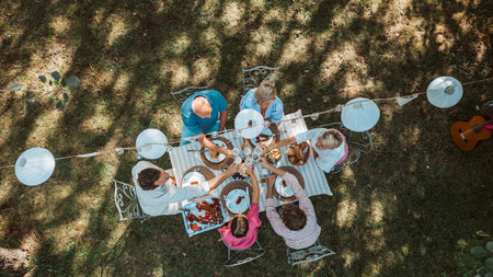 Areal view of multigenerational family toasting during outdoor barbecue party.の写真素材